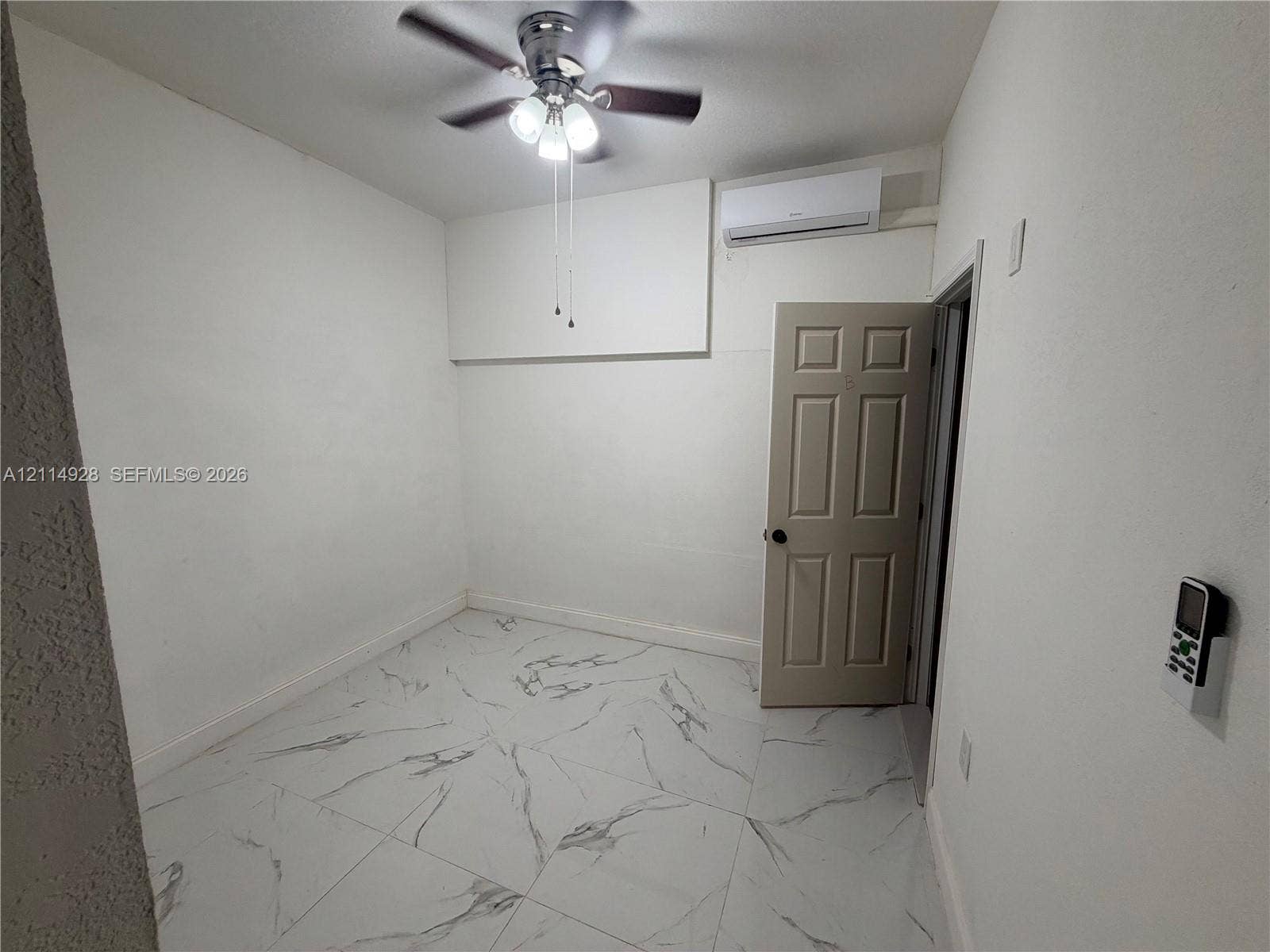 1411 SE 26th Road, Homestead, FL 33035 Large-format stone-style tile flooring, ceiling fan with integrated lighting, and wall-mounted ductless climate control system