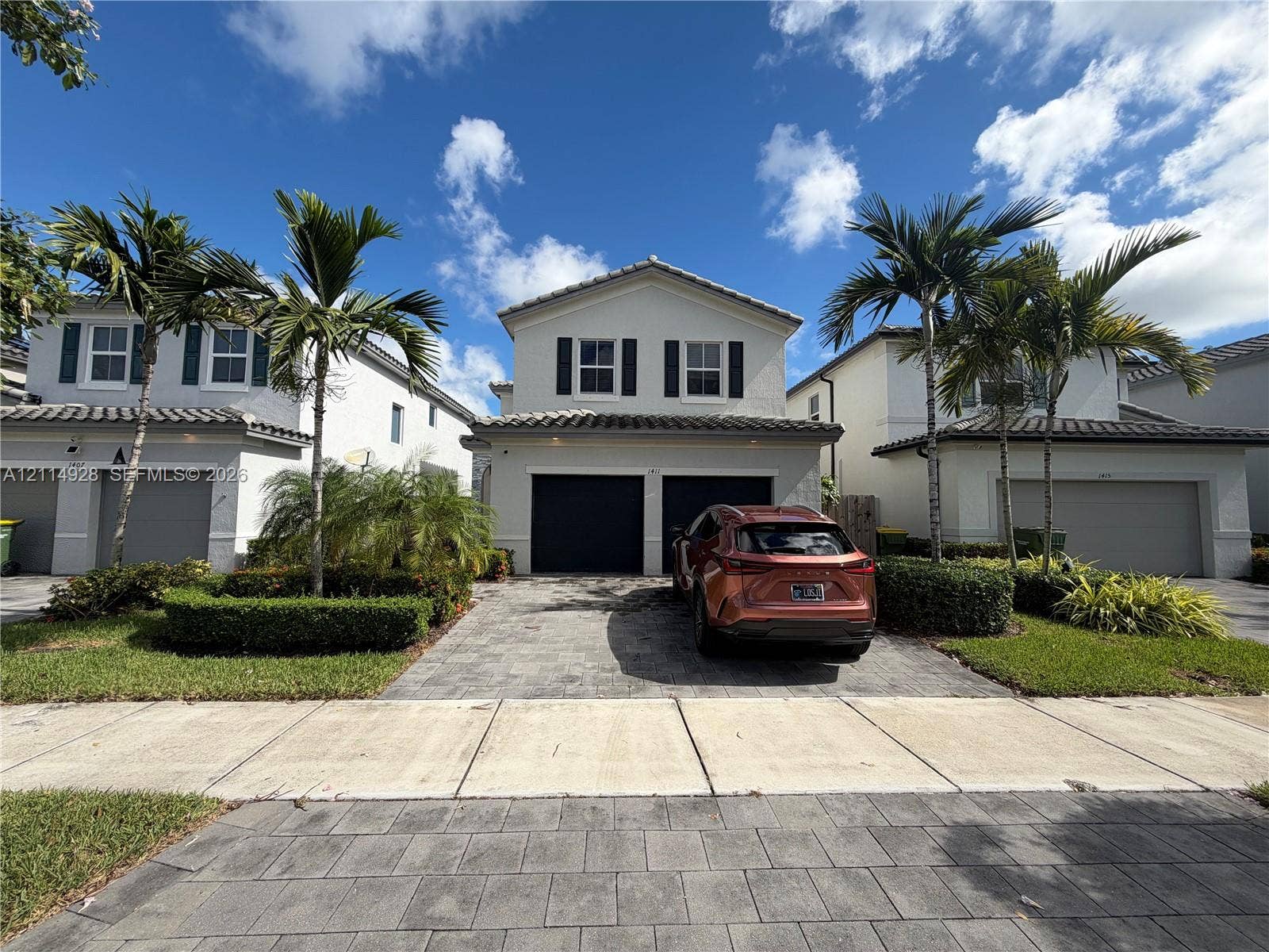 1411 SE 26th Road, Homestead, FL 33035 Two-story stucco exterior with a tiled roof, paver driveway, and a two-car garage