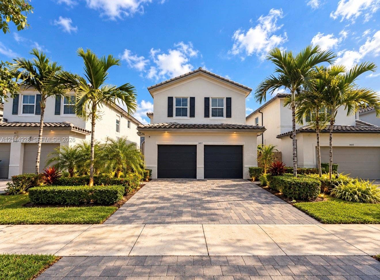 1411 SE 26th Road, Homestead, FL 33035 Two-story exterior featuring a stucco facade, concrete tile roof, paver driveway, two-car garage, and shuttered windows