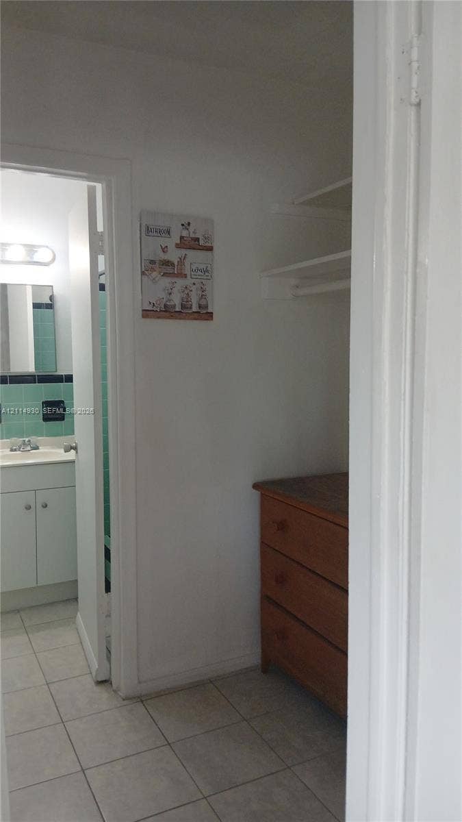 319 NE 2nd Street, #1, Hallandale Beach, Hallandale Beach, FL 33009 Walk-in closet with built-in shelving, tiled flooring, and a bathroom featuring a vanity with integrated sink and tile wall accents