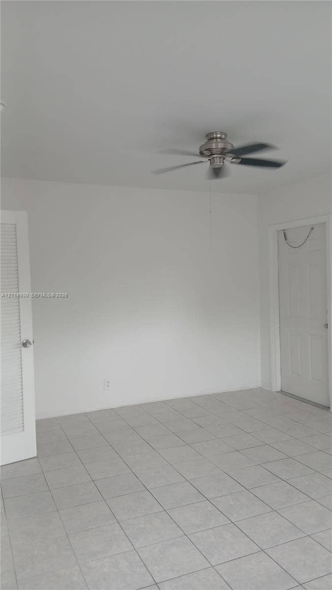 319 NE 2nd Street, #1, Hallandale Beach, Hallandale Beach, FL 33009 Interior room featuring neutral wall-to-wall ceramic tile flooring, a brushed-nickel ceiling fan, a louvered closet door, and a multi-panel door