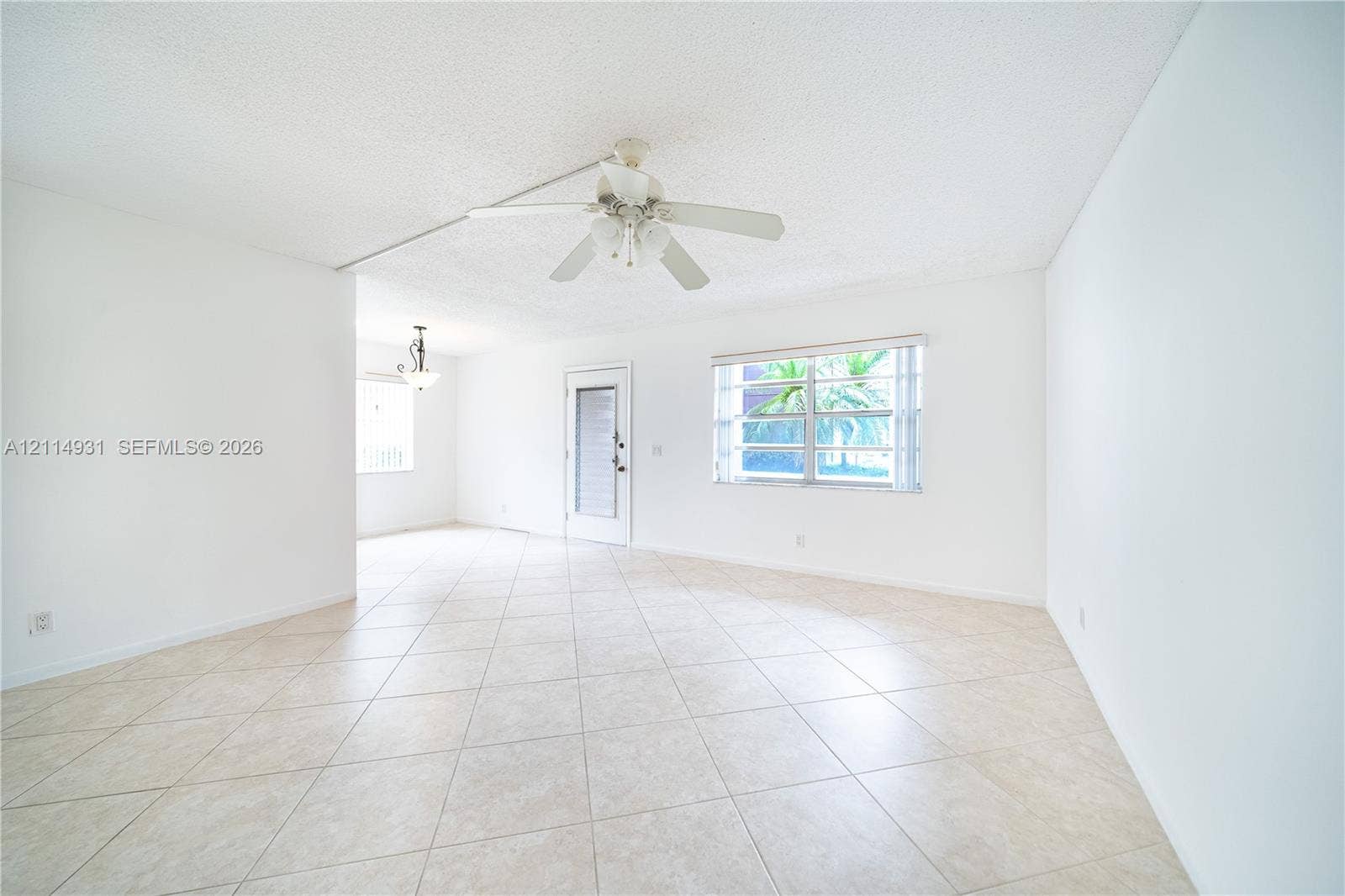 642 N Normandy N, #642, Delray Beach, Delray Beach, FL 33484 Open-concept interior featuring light-toned tile flooring, a multi-blade ceiling fan with integrated lighting, multi-pane windows, and a glass-panel exterior door