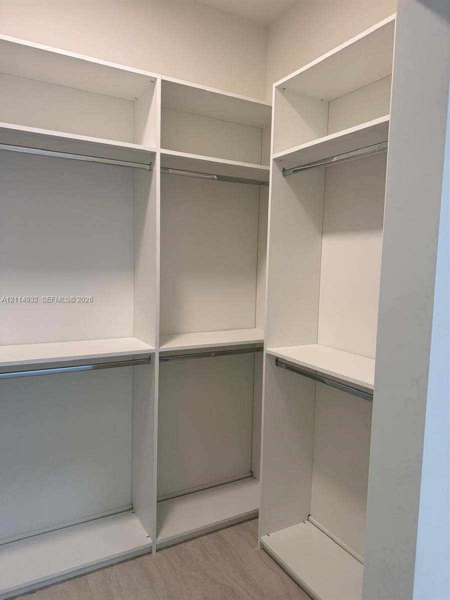 77 SE 5th Street, #607, Miami, FL 33141 Walk-in closet featuring white built-in shelving, multiple open storage compartments, and metal hanging rods
