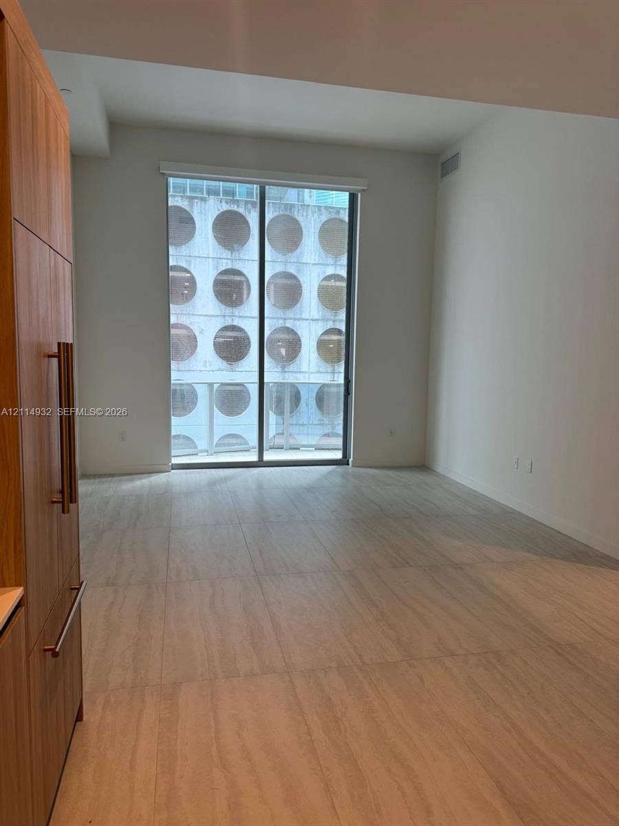 77 SE 5th Street, #607, Miami, FL 33141 Floor-to-ceiling sliding glass doors, full-height wood-finish cabinetry, and large-format tile flooring