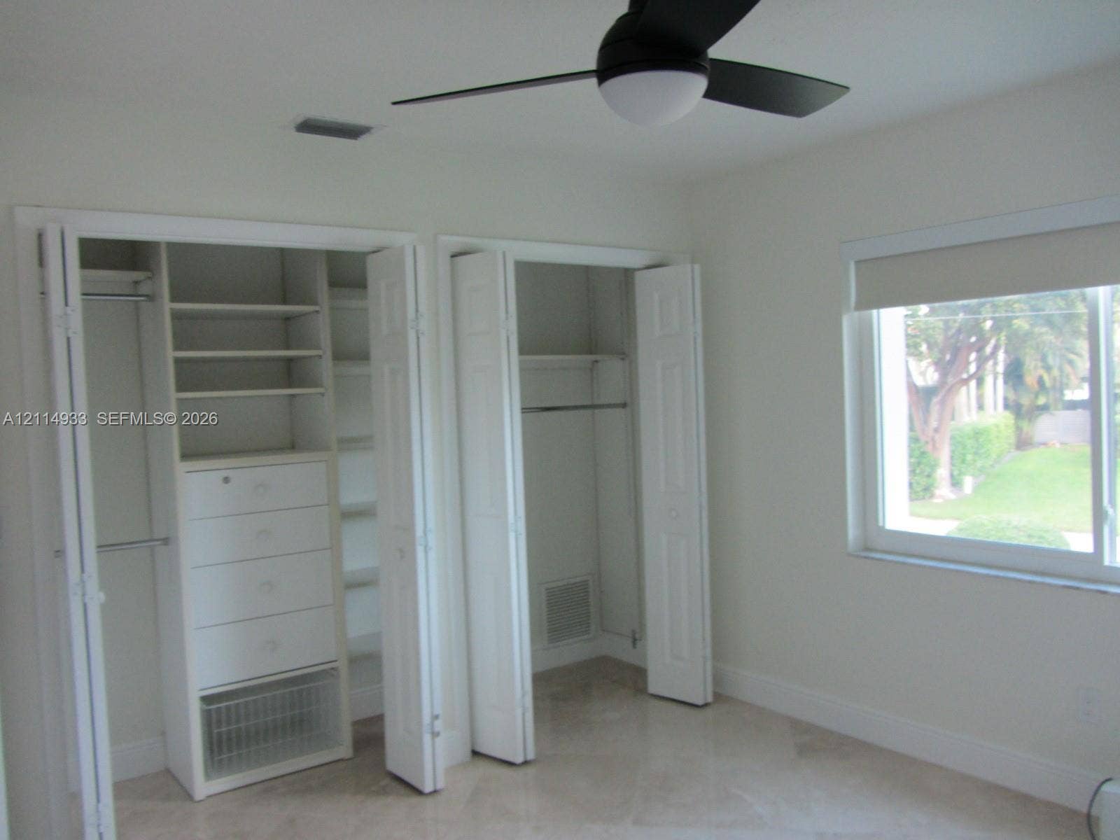 1001 Bella Vista Avenue, Coral Gables, Coral Gables, FL 33156 Dual closets with built-in shelving and integrated drawer storage, neutral tile flooring, and a ceiling fan with integrated light fixture