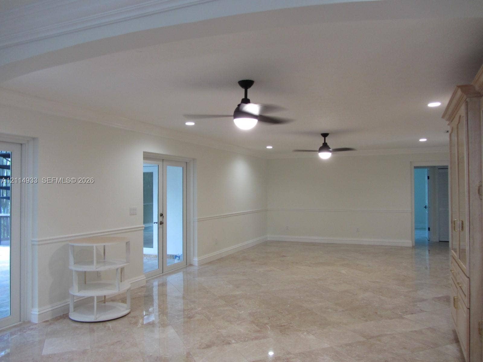 1001 Bella Vista Avenue, Coral Gables, Coral Gables, FL 33156 Polished stone flooring, crown molding, chair rail trim, dual ceiling fans with integrated lighting, and glass-paned French doors