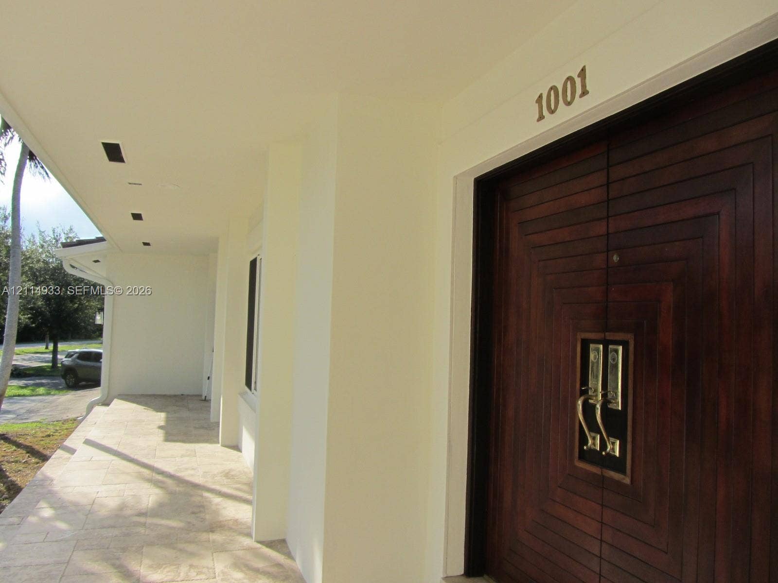 1001 Bella Vista Avenue, Coral Gables, Coral Gables, FL 33156 Covered entryway featuring natural stone tile flooring, recessed ceiling lighting, and double doors with dark wood finish and geometric relief detail