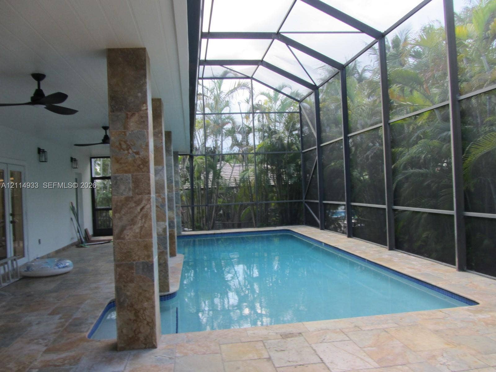 1001 Bella Vista Avenue, Coral Gables, Coral Gables, FL 33156 Screen-enclosed pool area featuring stone-tile decking, stone-clad structural pillars, recessed ceiling fans, and an attached covered patio