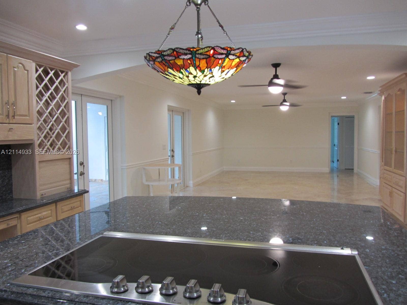 1001 Bella Vista Avenue, Coral Gables, Coral Gables, FL 33156 Kitchen featuring dark stone countertops, a glass-top cooktop, light wood cabinetry with built-in wine storage, recessed lighting, and a stained glass pendant fixture