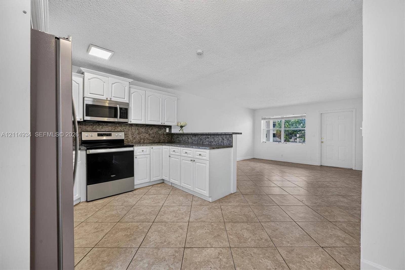 Kitchen featuring white cabinetry, stone-finish countertops, stainless steel appliances, and tile flooring