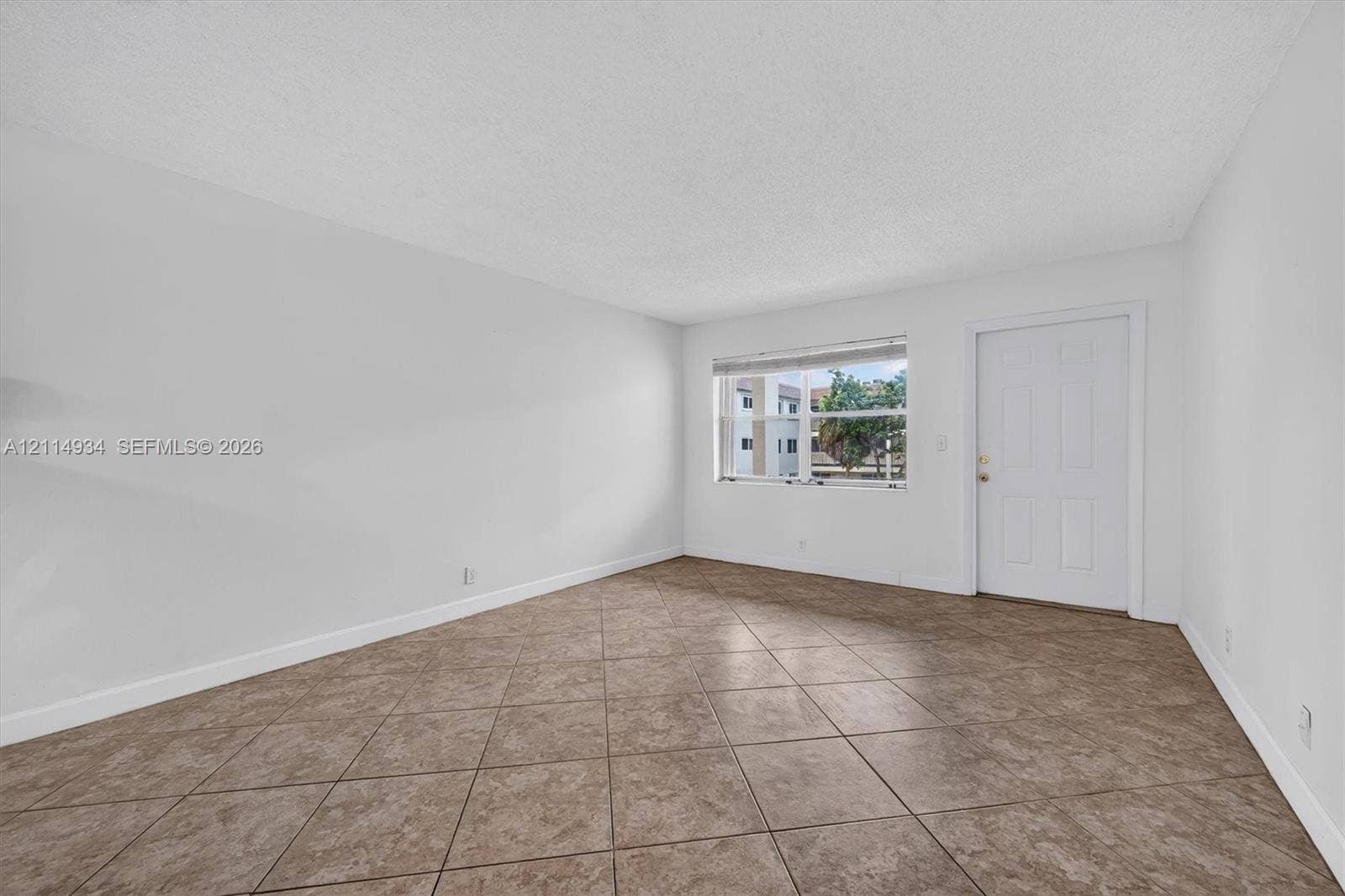 Neutral-toned room featuring diagonal-set tile flooring, white walls, and a recessed window with horizontal blinds