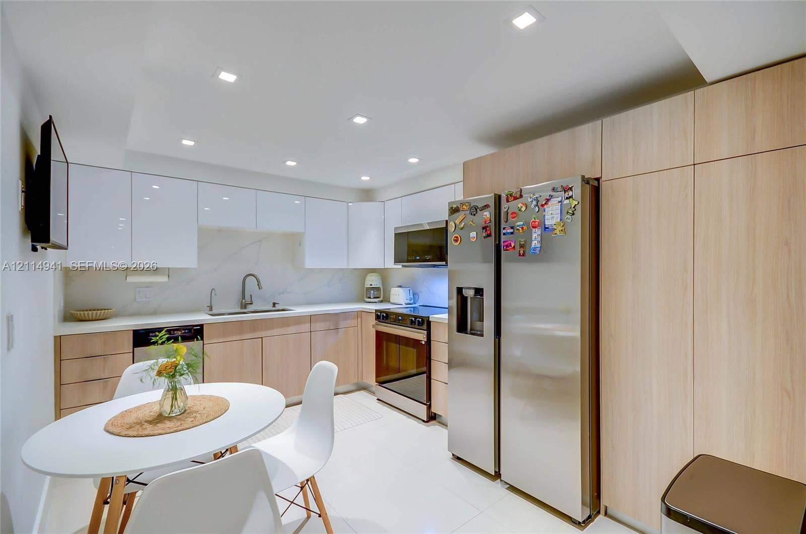 16175 Golf Club Road, #113, Weston, FL 33326 Kitchen featuring high-gloss upper cabinetry, wood-finish lower cabinetry, stone-style backsplash, integrated stainless steel appliances, and recessed lighting
