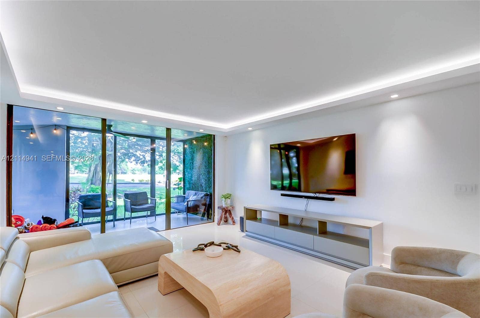 16175 Golf Club Road, #113, Weston, FL 33326 Living area featuring large-format tile flooring, recessed tray ceiling lighting, and floor-to-ceiling sliding glass doors
