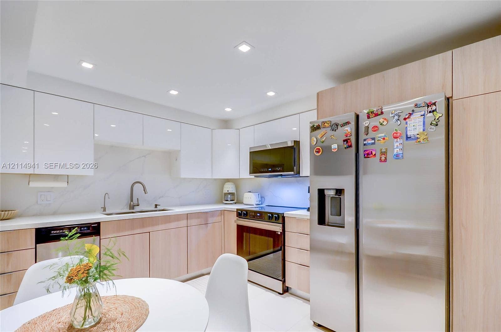 16175 Golf Club Road, #113, Weston, FL 33326 Kitchen featuring high-gloss white upper cabinetry, wood-finish base cabinetry, stone-style backsplash, integrated stainless steel appliances, and recessed ceiling lighting
