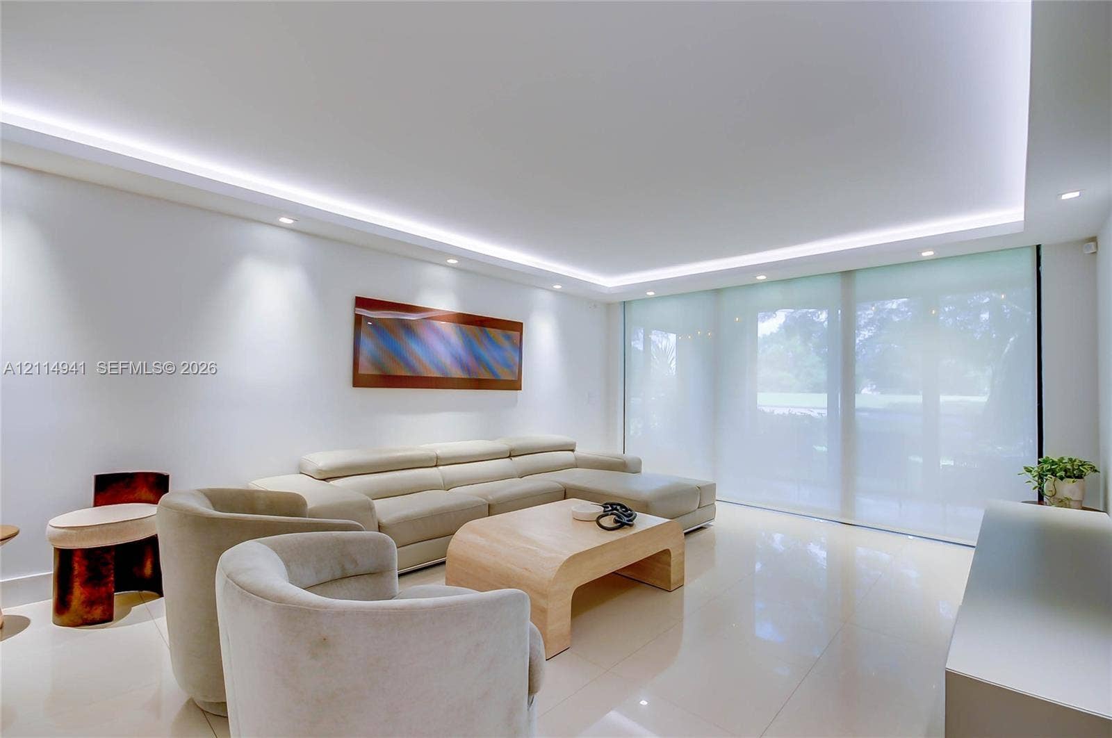 16175 Golf Club Road, #113, Weston, FL 33326 Expansive living space featuring polished light-toned tile flooring, recessed cove lighting, and floor-to-ceiling sliding glass doors with integrated roller shades