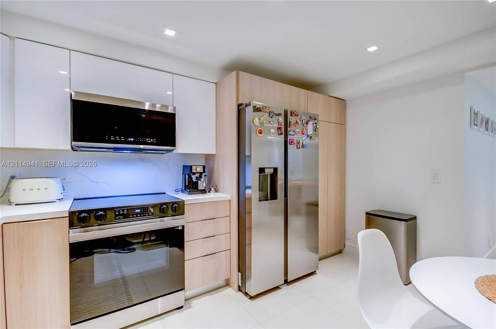 16175 Golf Club Road, #113, Weston, FL 33326 Kitchen featuring high-gloss white upper cabinetry, wood-finish base cabinetry, stone-surface backsplash, stainless steel appliances, and recessed ceiling lighting