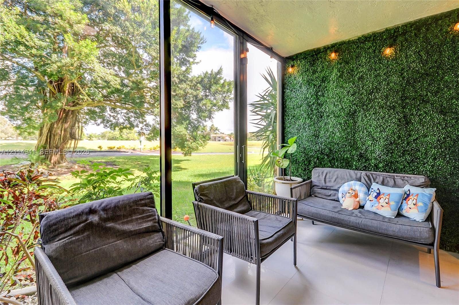 16175 Golf Club Road, #113, Weston, FL 33326 Enclosed porch featuring floor-to-ceiling glass paneling, tile flooring, and a decorative artificial hedge wall with integrated overhead lighting