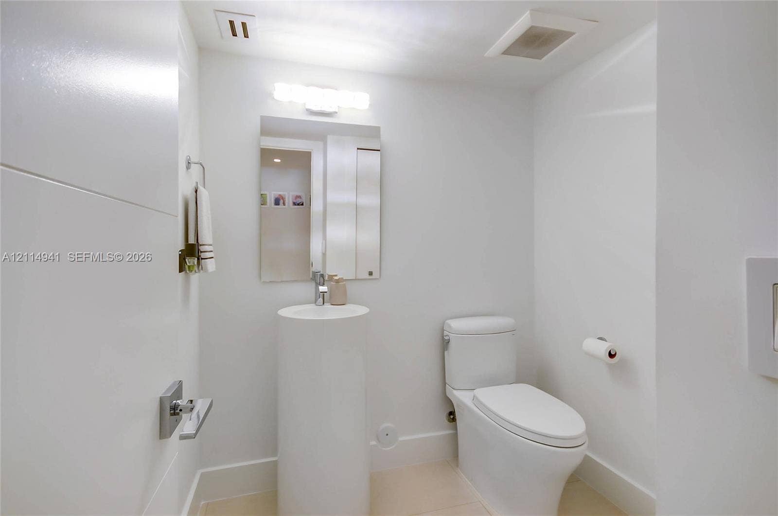 16175 Golf Club Road, #113, Weston, FL 33326 Cylindrical pedestal sink, rectangular wall-mounted mirror, chrome single-handle faucet, and white high-profile toilet