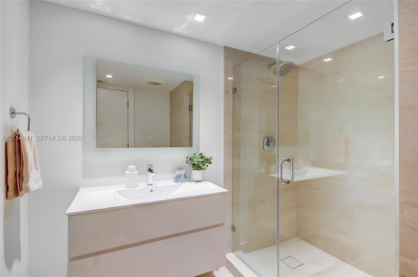 16175 Golf Club Road, #113, Weston, FL 33326 Floating vanity with an integrated sink, frameless glass-enclosed shower, stone-surround shower wall, recessed lighting, and a wall-mounted mirror