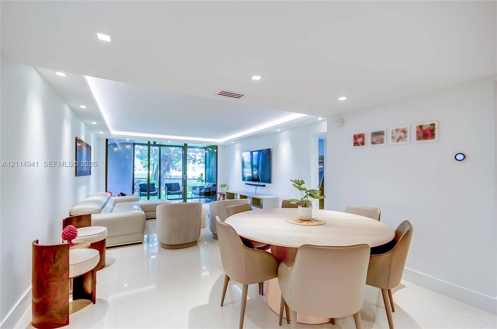 16175 Golf Club Road, #113, Weston, FL 33326 Open-concept living space featuring high-gloss tile flooring, recessed lighting, ceiling tray with perimeter cove lighting, and floor-to-ceiling glass panel sliding doors