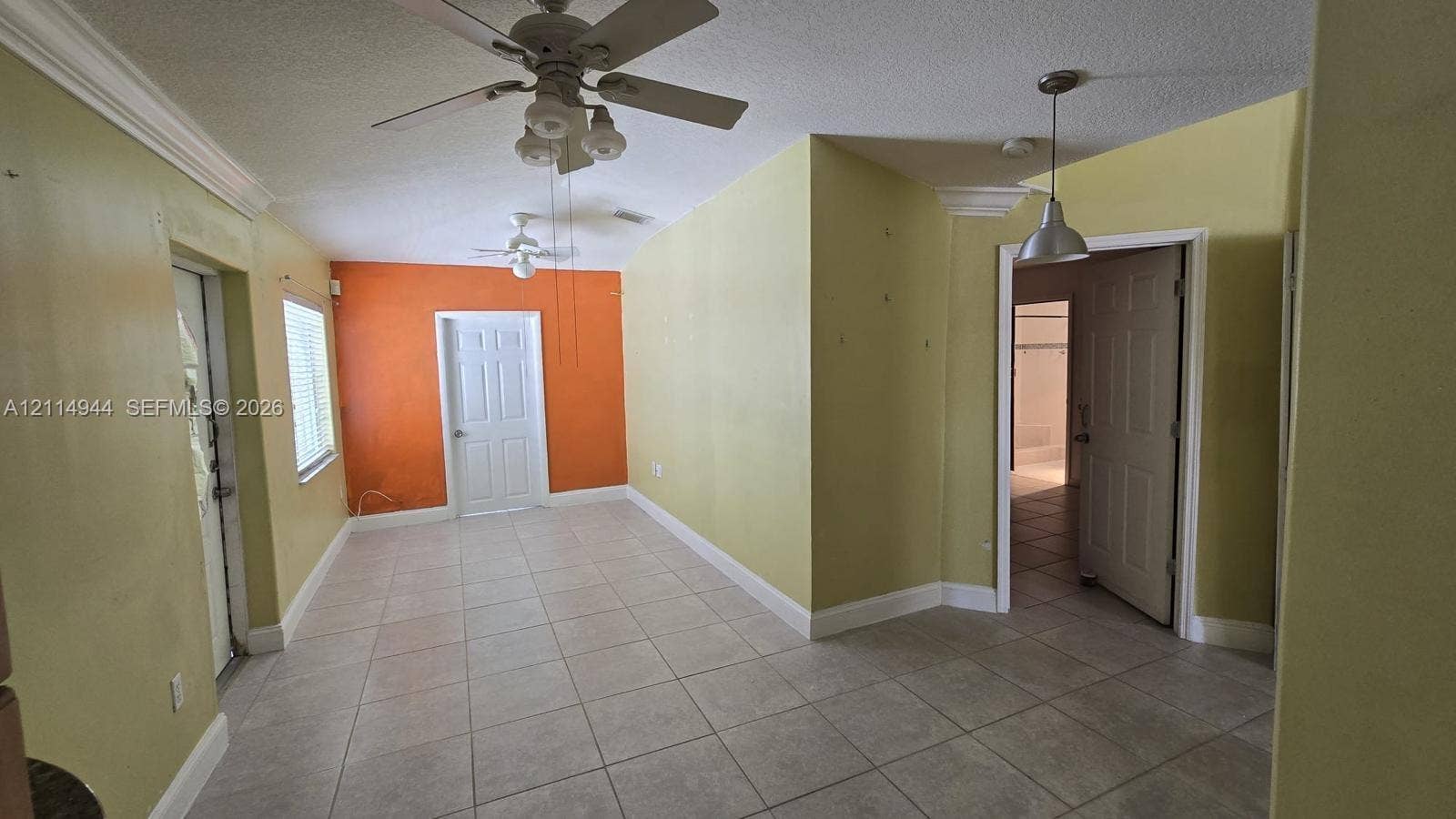 Interior space featuring light-colored tile flooring, multiple ceiling fans, recessed crown molding, and hanging pendant lighting