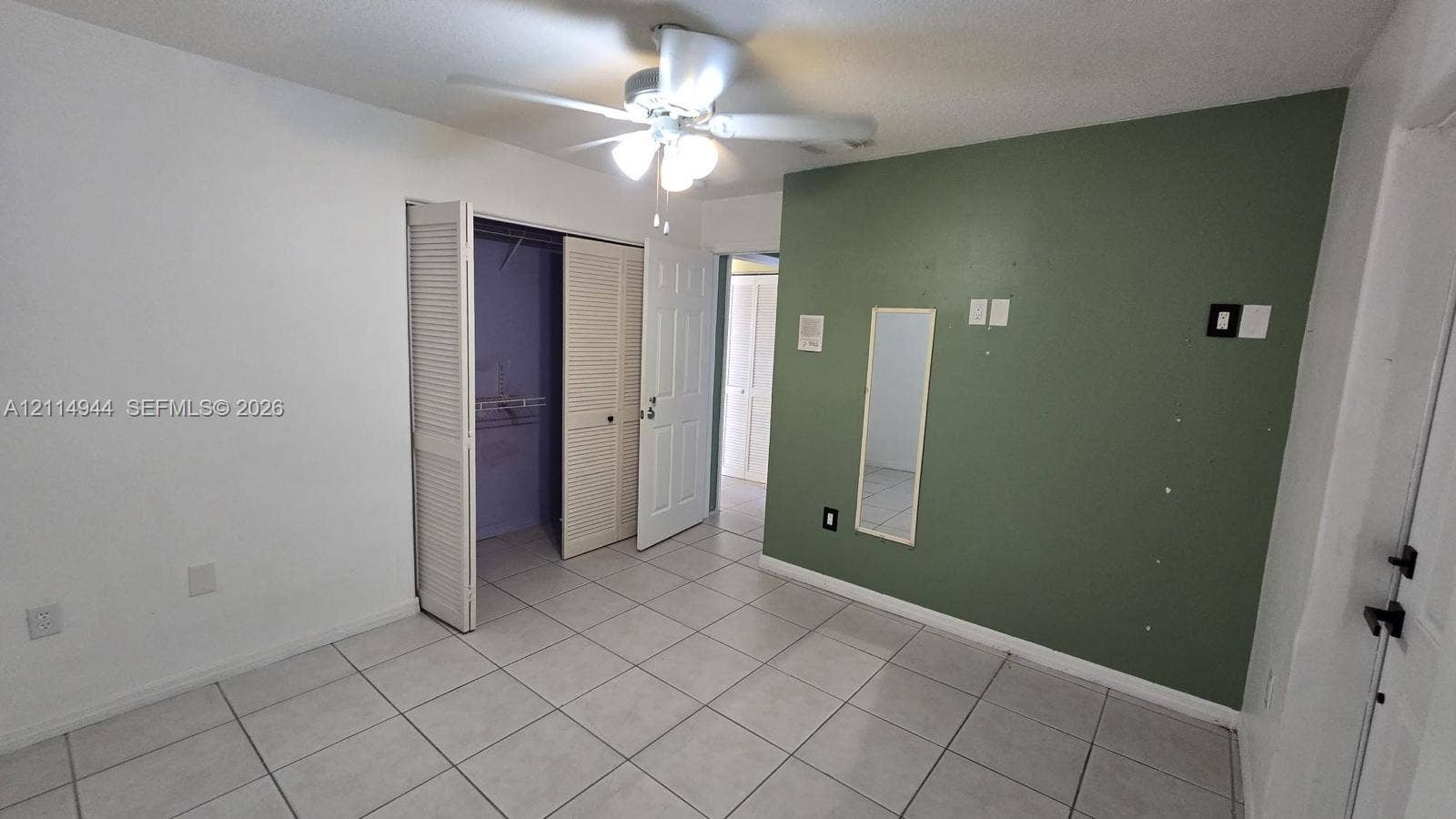 Neutral tile flooring, ceiling fan with light fixture, bifold closet doors, and interior paneled doors