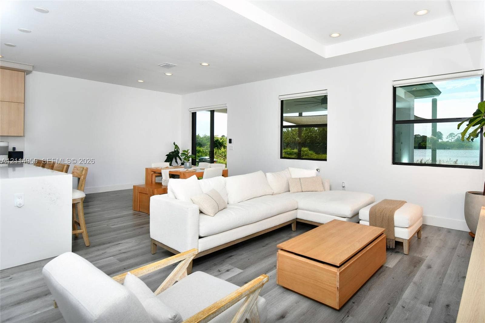 8017 Sunrise Circle, Labelle, FL 33935 Open-concept living space featuring wood-finish flooring, recessed lighting, a coffered ceiling, a large kitchen island with light-toned surfacing, and black-framed windows