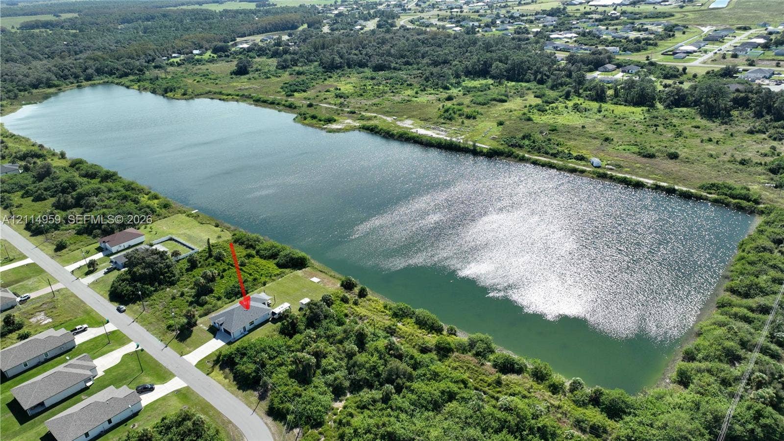 8017 Sunrise Circle, Labelle, FL 33935 Aerial perspective of a property featuring a single-family residence, concrete driveway, and direct water frontage on a large lake