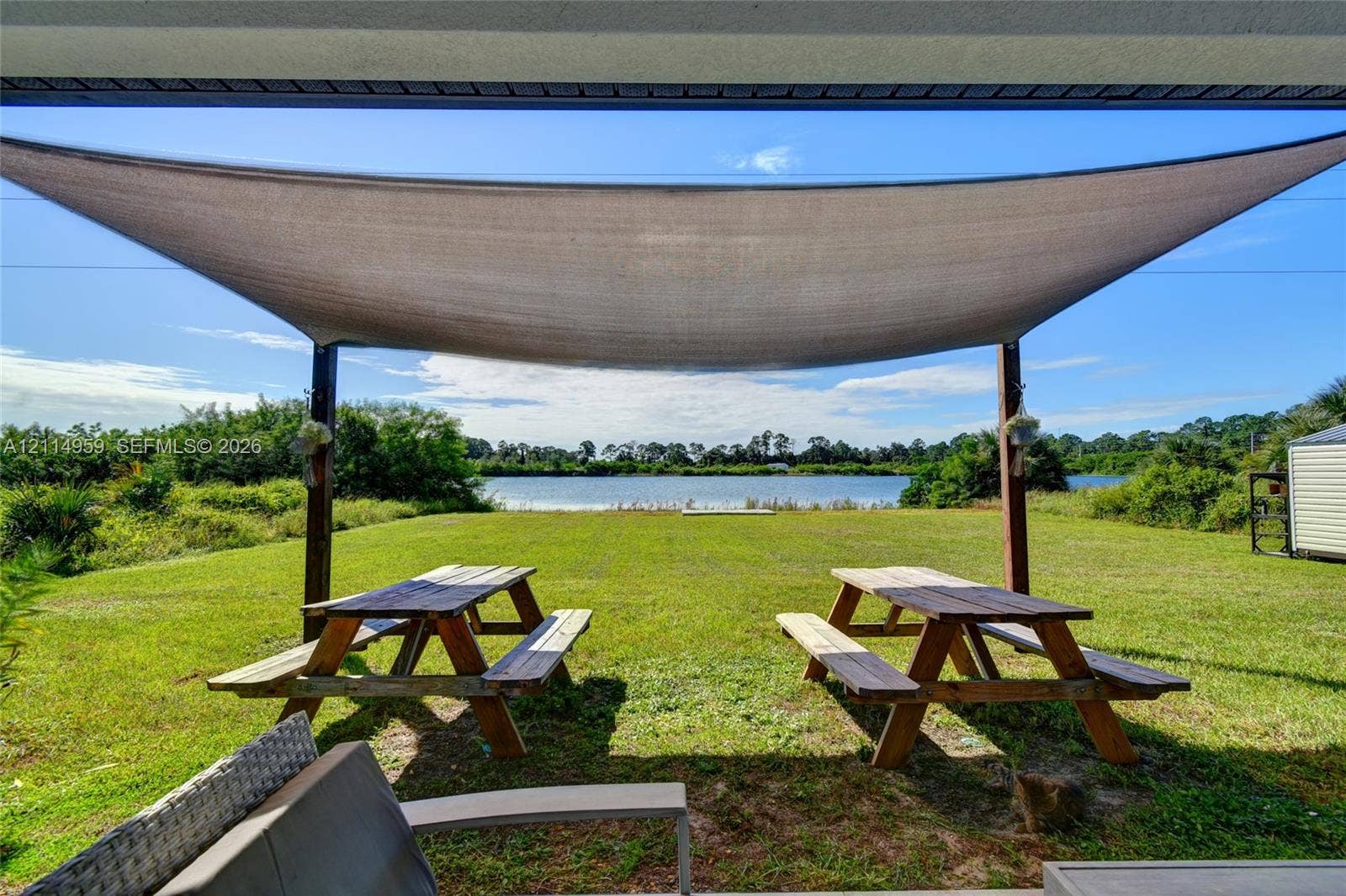 8017 Sunrise Circle, Labelle, FL 33935 Covered outdoor space featuring a fabric shade canopy, expansive lawn, and waterfront footage