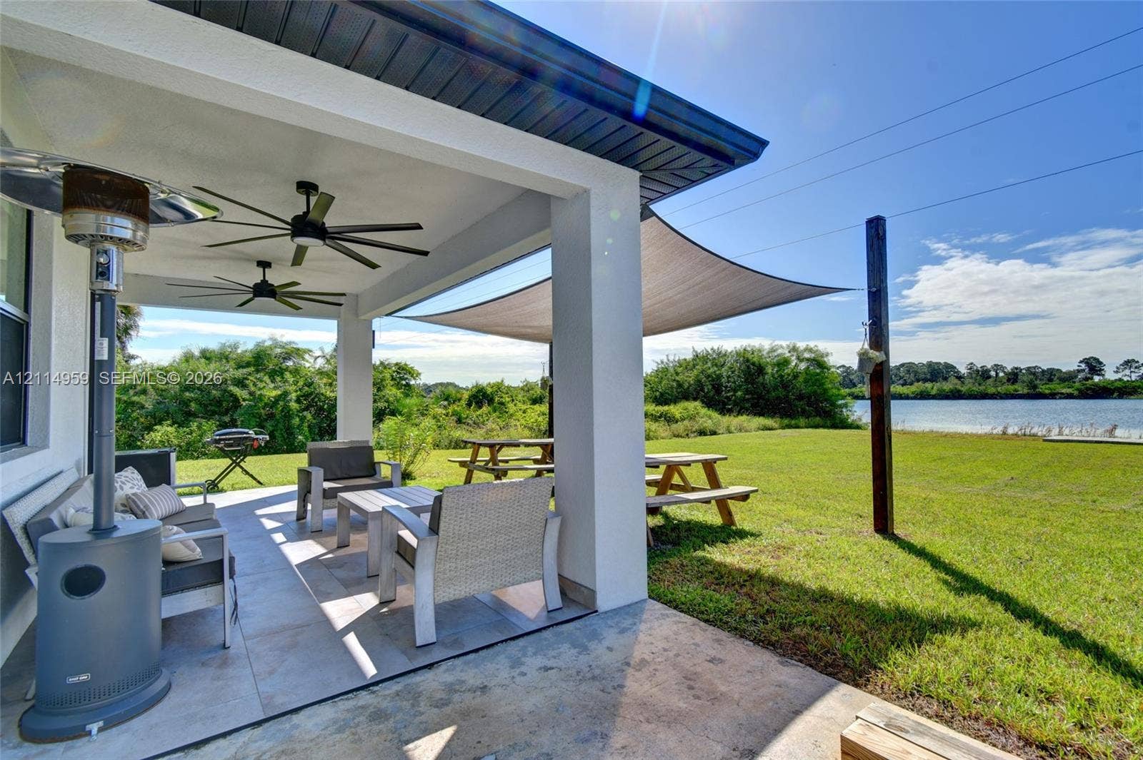 8017 Sunrise Circle, Labelle, FL 33935 Covered patio featuring large-format tile flooring, dual ceiling fans, and structural support columns