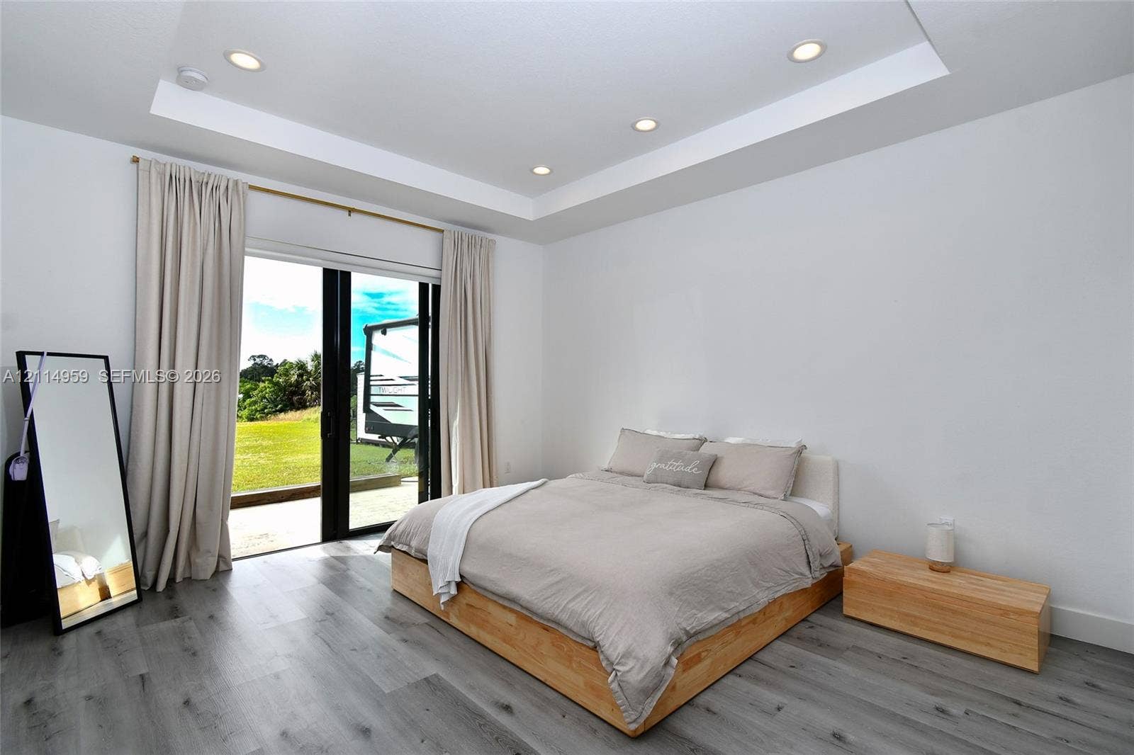8017 Sunrise Circle, Labelle, FL 33935 Tray ceiling with recessed lighting, wood-finish flooring, and expansive black-framed sliding glass doors