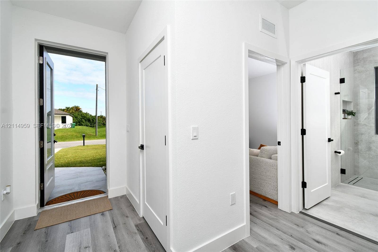 8017 Sunrise Circle, Labelle, FL 33935 Entryway featuring wood-finish flooring, shaker-style interior doors with matte black hardware, and an exterior door with glass inlay