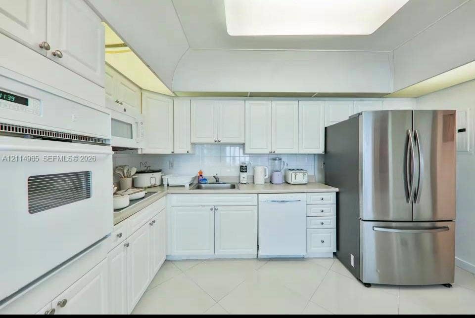 19370 Collins Avenue, #414, Sunny Isles Beach, FL 33160 Kitchen featuring white shaker-style cabinetry, solid-surface countertops, recessed ceiling lighting, a stainless steel refrigerator, and built-in wall oven