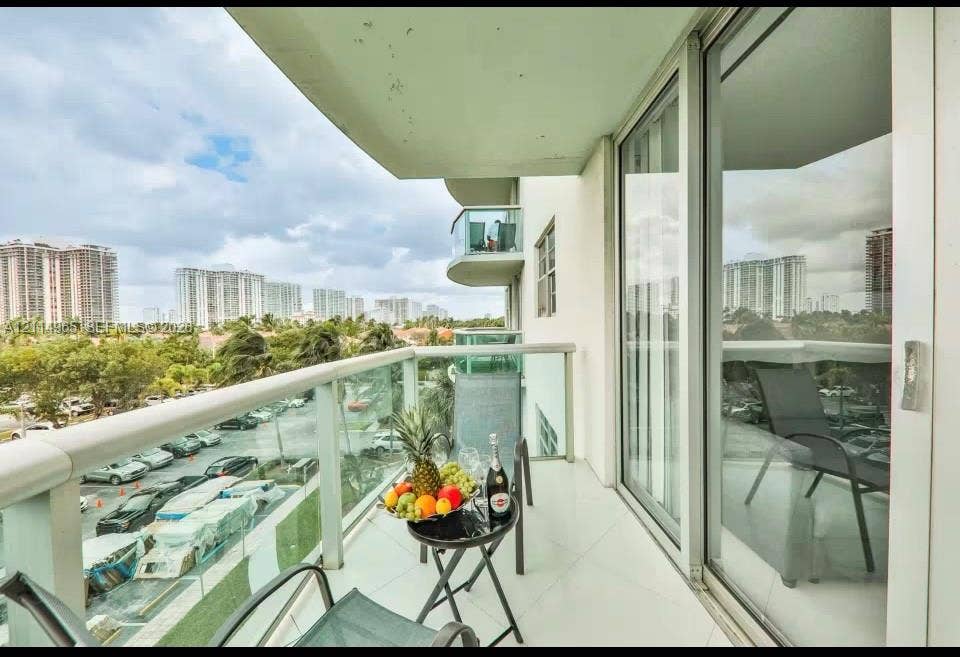 19370 Collins Avenue, #414, Sunny Isles Beach, FL 33160 Private balcony featuring polished tile flooring, glass panel railings with metal framing, and full-height sliding glass doors