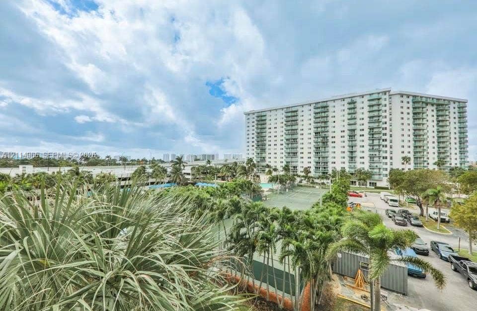 19370 Collins Avenue, #414, Sunny Isles Beach, FL 33160 High-rise residential building featuring private balconies, outdoor tennis courts, and mature palm trees