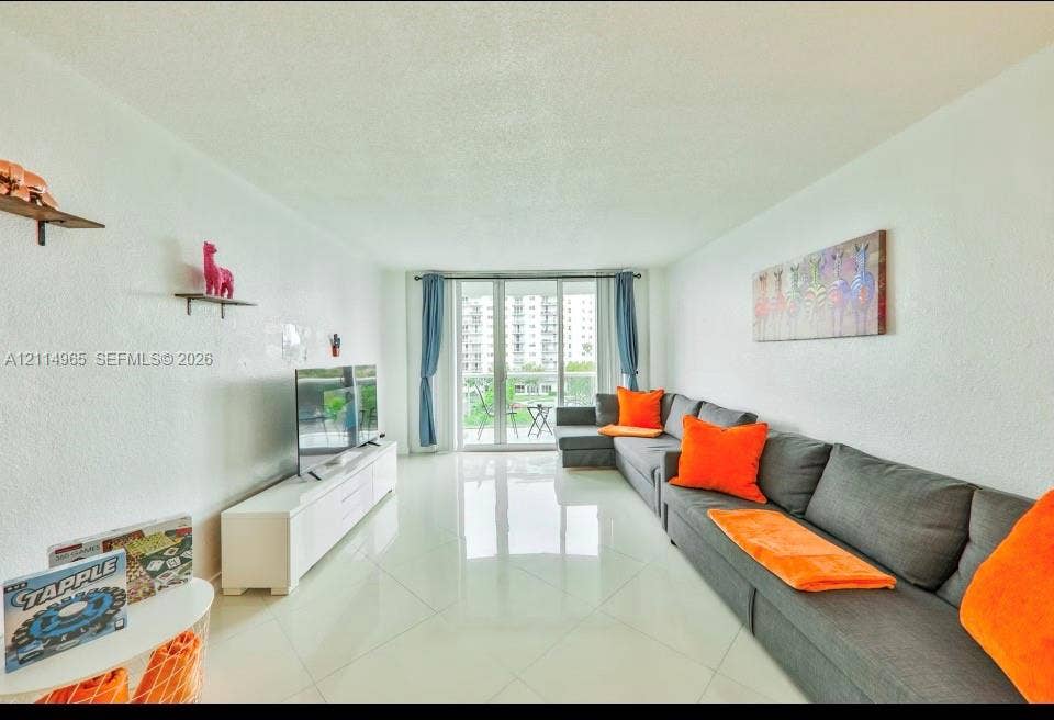 19370 Collins Avenue, #414, Sunny Isles Beach, FL 33160 Living space featuring polished tile flooring, neutral walls, and a multi-panel glass door providing natural light