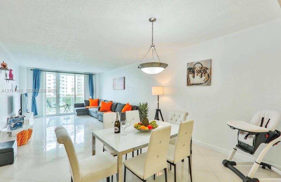 19370 Collins Avenue, #414, Sunny Isles Beach, FL 33160 Open-concept living space featuring high-gloss tile flooring, an oversized sliding glass door, and a multi-light metal pendant fixture