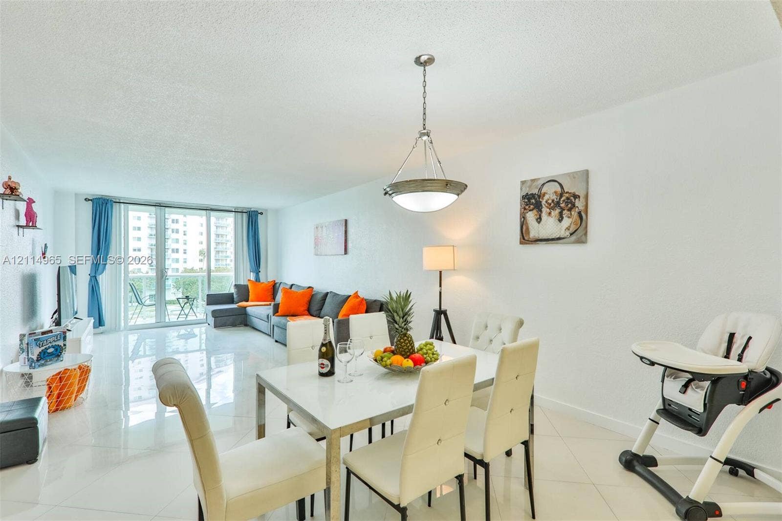 19370 Collins Avenue, #414, Sunny Isles Beach, FL 33160 Open-concept living space featuring high-gloss tile flooring, floor-to-ceiling sliding glass doors, and a decorative pendant light fixture
