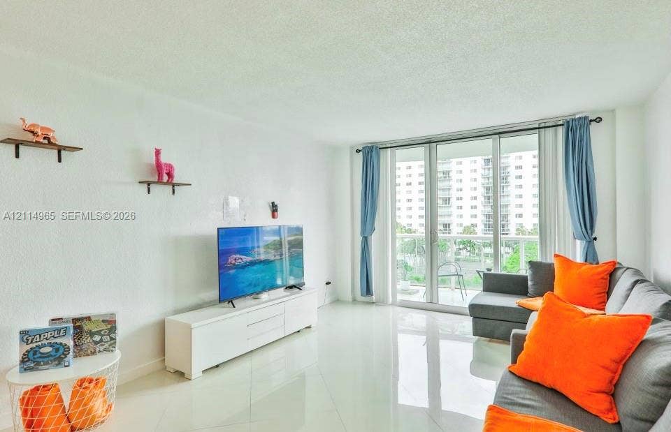 19370 Collins Avenue, #414, Sunny Isles Beach, FL 33160 Living space featuring polished tile flooring, white walls, and sliding glass doors with access to an exterior balcony