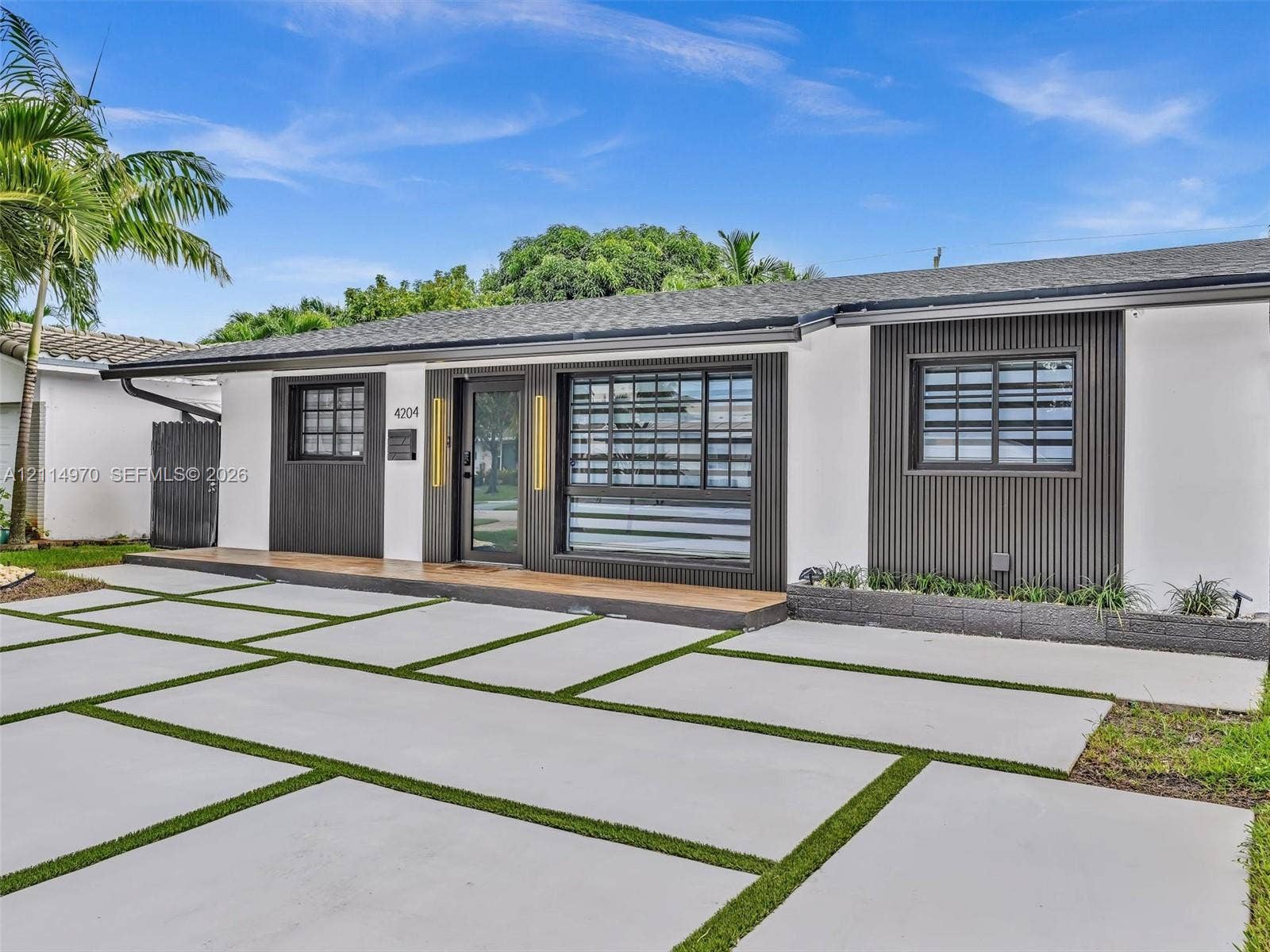 4204 Van Buren Street, Hollywood, Hollywood, FL 33021 Contemporary exterior featuring smooth white stucco, vertical dark-tone siding accents, custom multi-pane window configurations, and a concrete paver driveway with integrated grass joints