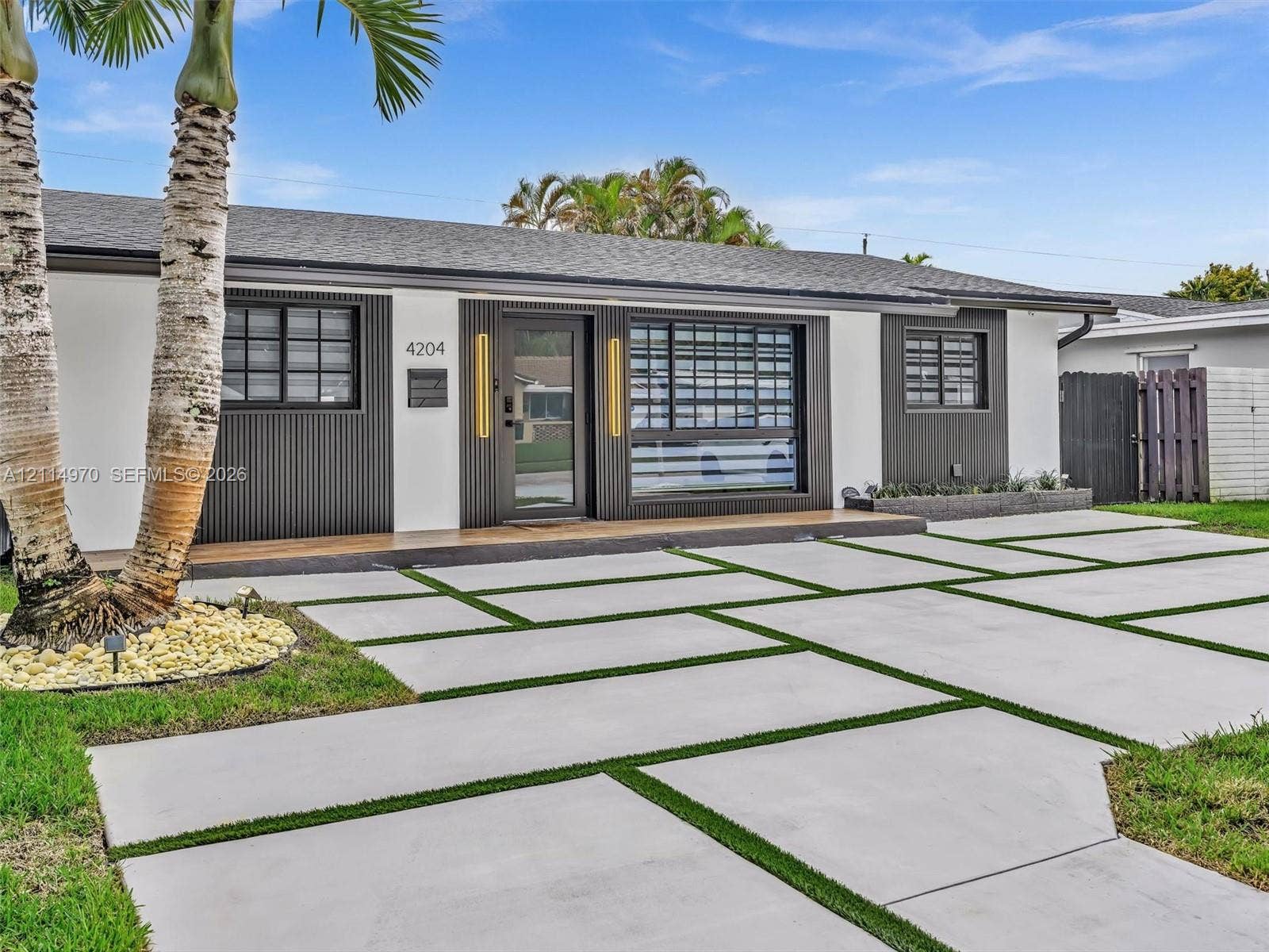 4204 Van Buren Street, Hollywood, Hollywood, FL 33021 Contemporary exterior featuring a contrasting facade of white stucco and dark vertical slat detailing, geometric concrete paver driveway with turf inserts, and low-profile hardscaping