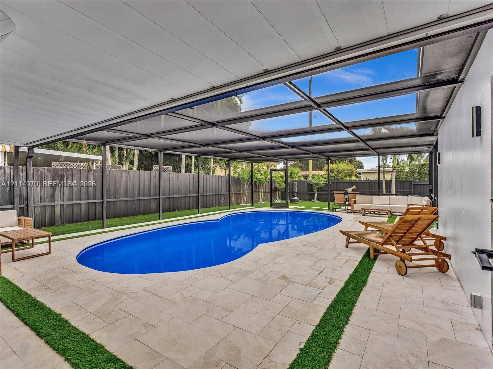 4204 Van Buren Street, Hollywood, Hollywood, FL 33021 Screen-enclosed patio area featuring an inground pool, stone-paver decking, integrated turf borders, and perimeter privacy fencing