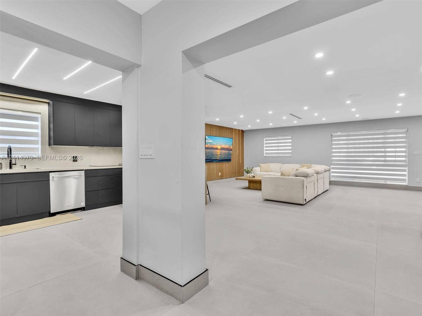 4204 Van Buren Street, Hollywood, Hollywood, FL 33021 Open-concept interior featuring large-format tile flooring, matte charcoal cabinetry, recessed ceiling lighting, and a wood-slat accent wall