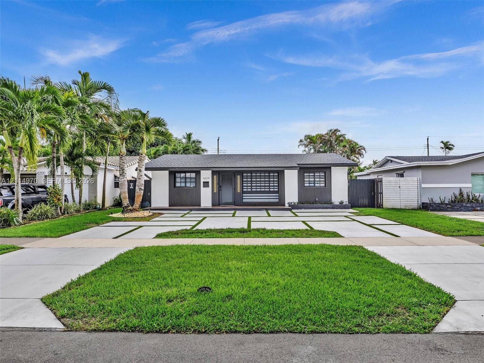 4204 Van Buren Street, Hollywood, Hollywood, FL 33021 Single-story exterior featuring a high-contrast facade, linear concrete paver driveway with integrated turf, multi-pane accent windows, and mature landscaping