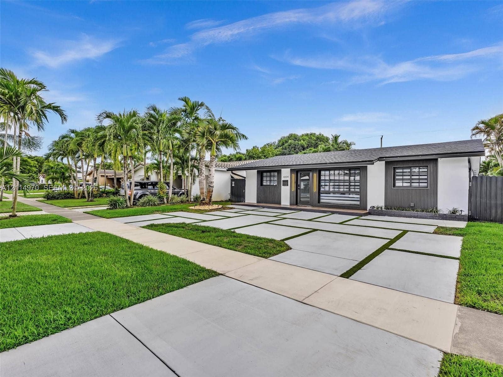 4204 Van Buren Street, Hollywood, Hollywood, FL 33021 Single-story exterior featuring a grid-pattern concrete driveway, manicured lawn, mature palms, and dark-finished exterior paneling