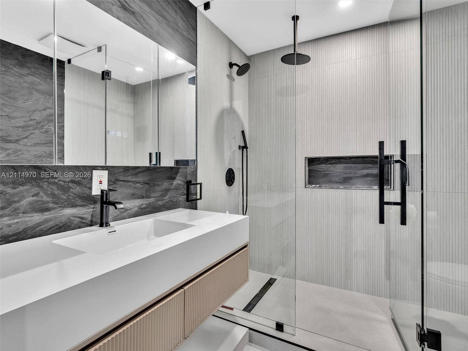 4204 Van Buren Street, Hollywood, Hollywood, FL 33021 Floating vanity with a smooth solid-surface countertop and integrated sink, complemented by a recessed mirror, fluted-texture cabinetry, a glass-enclosed shower with a rainfall showerhead, and a built-in shower niche