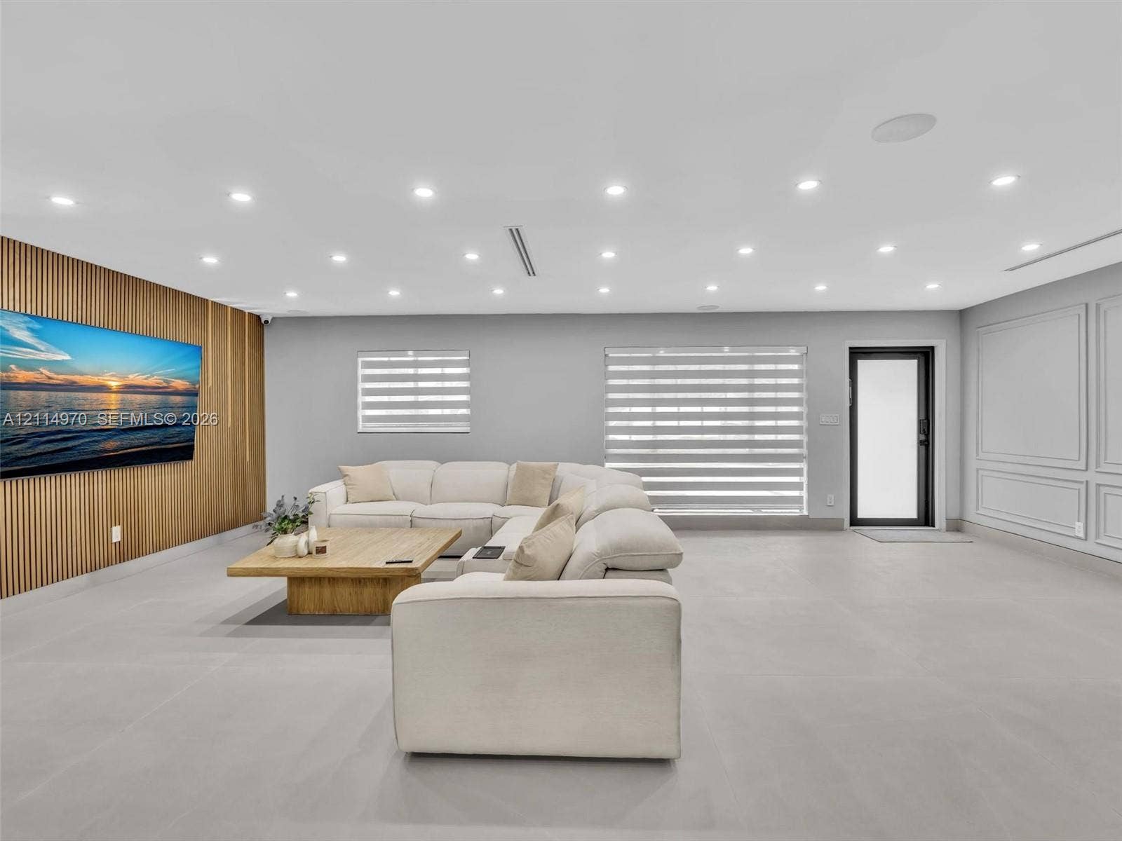 4204 Van Buren Street, Hollywood, Hollywood, FL 33021 Spacious interior featuring a vertical wood-slat accent wall, neutral large-format tile flooring, recessed ceiling lighting, and decorative wall molding