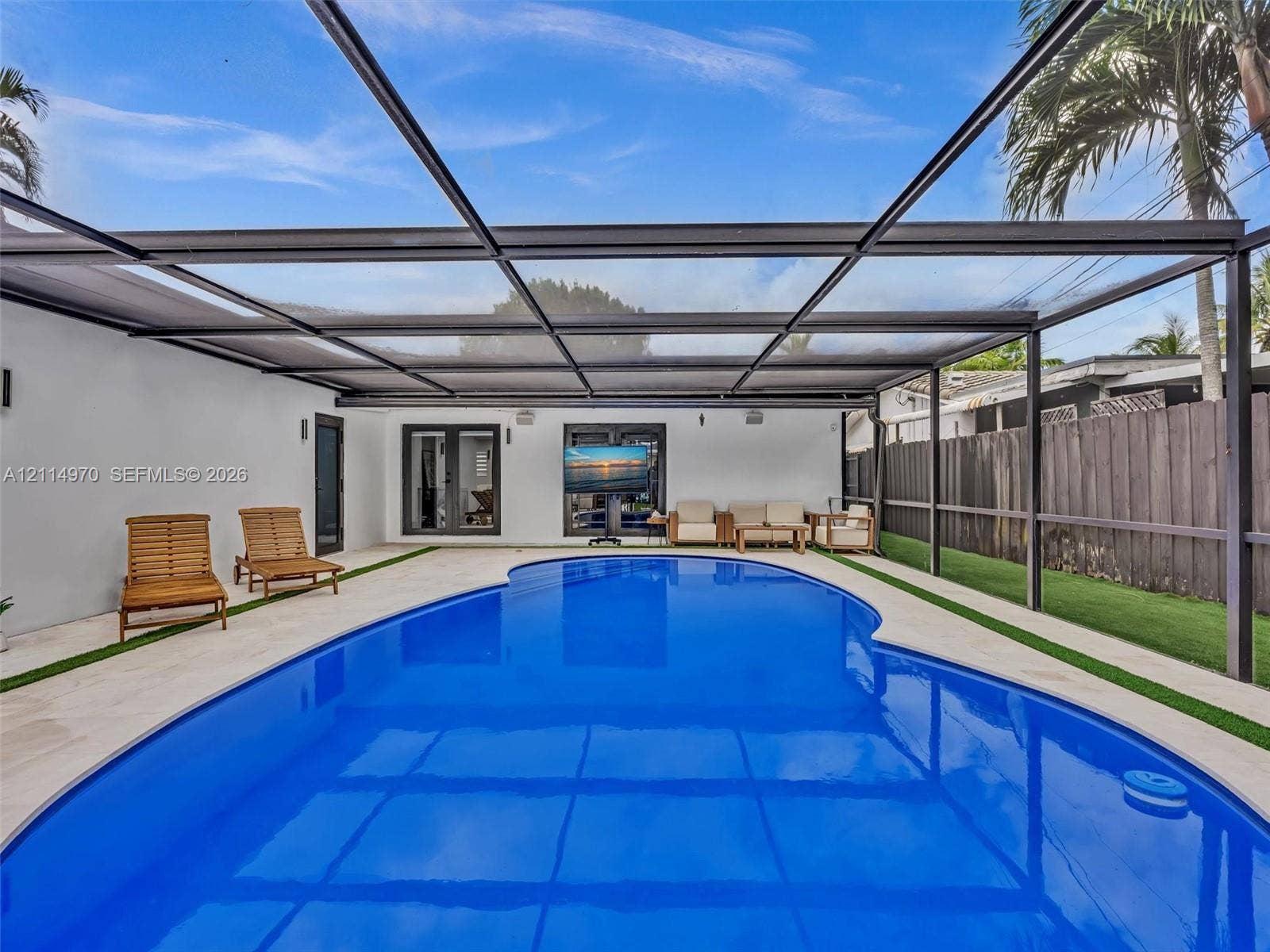 4204 Van Buren Street, Hollywood, Hollywood, FL 33021 In-ground pool enclosed by a metal-framed screen structure, light-toned paved decking, artificial turf borders, and double-glass door entry