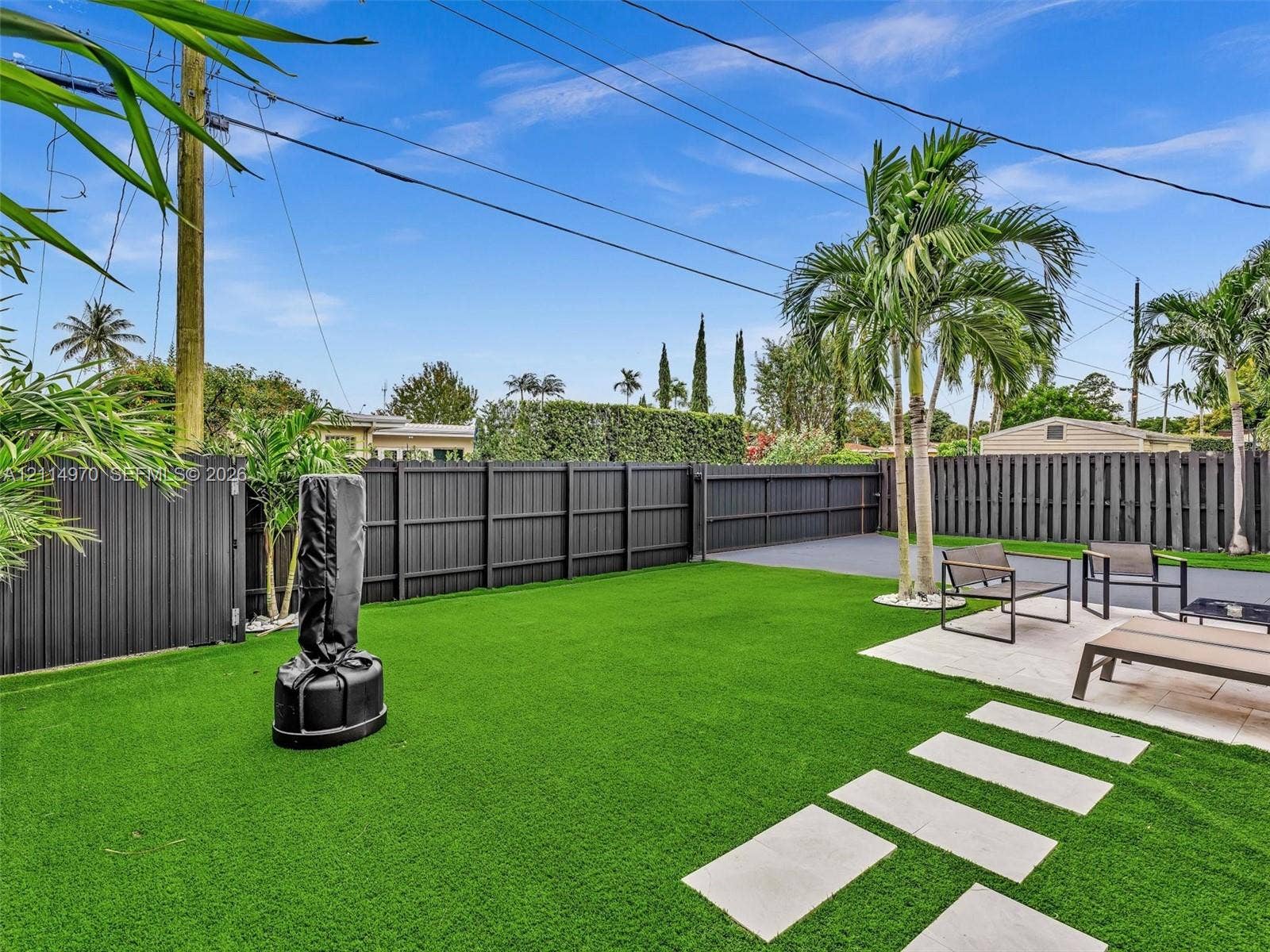 4204 Van Buren Street, Hollywood, Hollywood, FL 33021 Backyard featuring synthetic turf, paver patio, tall privacy fencing, and established palm trees