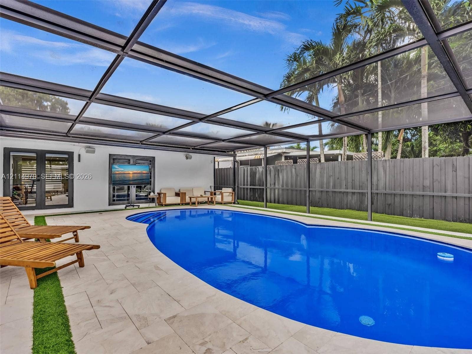 4204 Van Buren Street, Hollywood, Hollywood, FL 33021 Screened-in pool area featuring light-toned stone decking, inset synthetic turf, a built-in step entry, and dark-finished metal framing